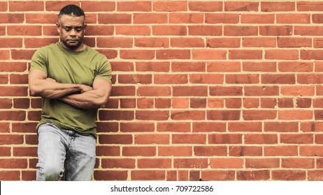 Fit man leaning against wall, in thought - Powered by Shutterstock
