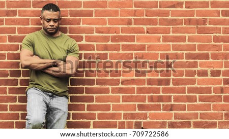 Fit man leaning against wall, in thought
