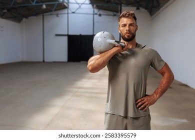 Fit man looking at the camera and posing while holding a weight at the gym