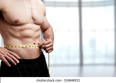 Fit Man Measuring His Waist After A Workout In The Gym