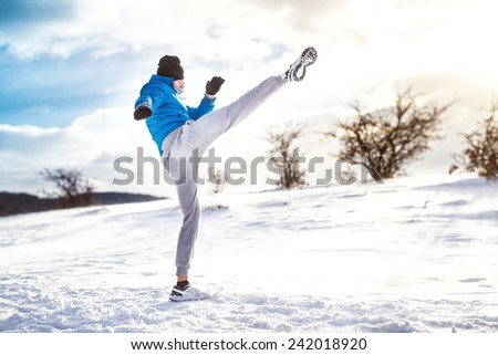 Fit man practicing a kick shot outdoor in snow. Fitness player training and practicing outside on a cold winter day