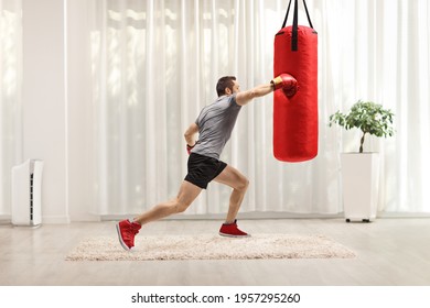 Fit Man Punching A Boxing Bag At Home