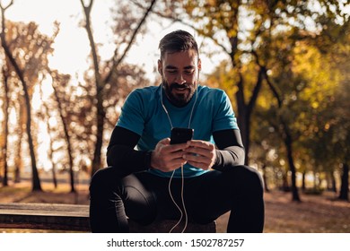 Fit Man Rest In The Park After Jogging,he Has Earphone And Mobile Phone.