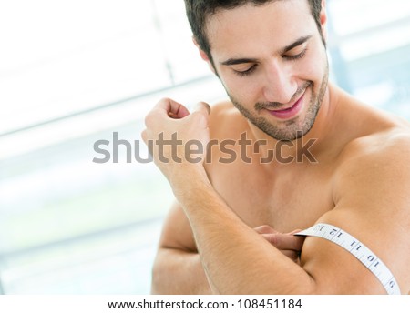 Fit man showing off his muscles and measuring them