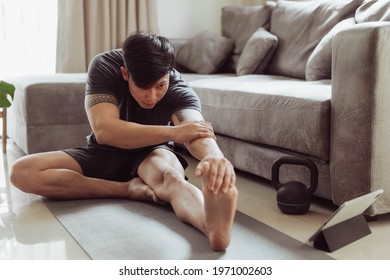 Fit Man In Sportwear Streching After Exercise At Home. Young Asian Man Streching Before Workout.