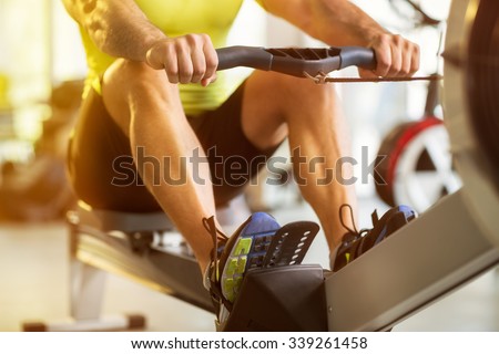 Fit man training on row machine in gym
