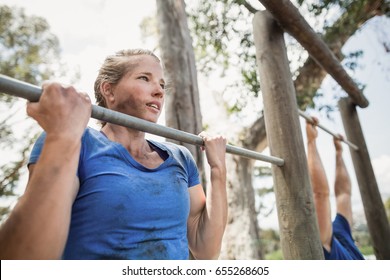 Fit man and woman performing pull-ups on bar during obstacle course in boot camp - Powered by Shutterstock