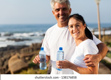 fit mature couple drinking water at the beach after exercise - Powered by Shutterstock