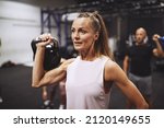 Fit mature woman in sportswear lifting a dumbbell during a strength training session at the gym