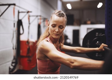 Fit mature woman in sportswear preparing to lift some heavy weights during a strength training workout at the gym - Shutterstock ID 2120149769