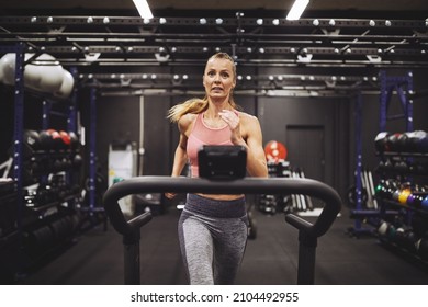 Fit mature woman in sportswear running on a treadmill during an exercise session out at a gym - Shutterstock ID 2104492955