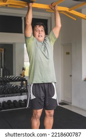 A Fit Middle Aged Asian Man Hangs On The Pull Up Bar At The Gym.