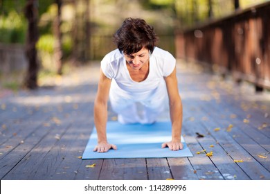 fit middle aged woman doing pushups outdoors