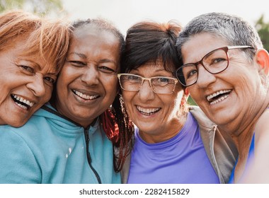 Fit multiracial senior women having fun after yoga class at city park - Elderly female friends taking a selfie while smiling on camera - Powered by Shutterstock