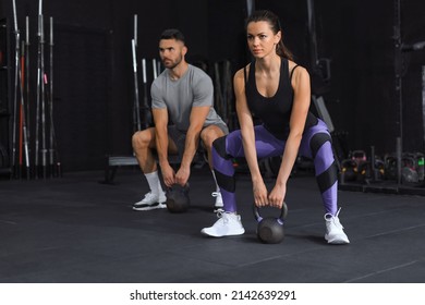 Fit and muscular couple focused on lifting a dumbbell during an exercise class in a gym - Shutterstock ID 2142639291