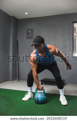 A fit muscular guy prepares to do a set of single arm shoulder thrusters with a kettlebell. Advance compound exercise.