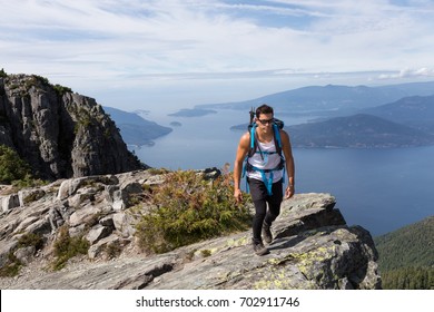 Fit And Muscular Latin American Male Hiker Is Walking Near The Cliff Of The Mountain. Picture Taken On The Way Up To The Lions Peaks, North Of Vancouver, British Columbia, Canada.