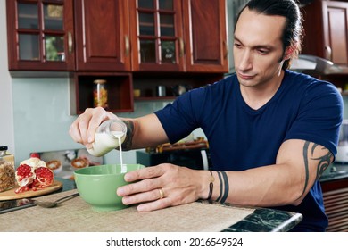 Fit Muscular Man Pouring Fresh Milk In Bowl When Preparing Healthy High Protein Breakfast