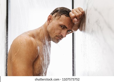 Fit muscular man taking a shower