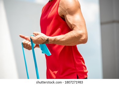 Fit Muscular Sports Man Doing Bicep Curl Exercise With Resistance Band In The Open Air