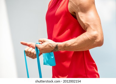 Fit Muscular Sports Man Doing Bicep Curl Exercise With Resistance Band In The Open Air