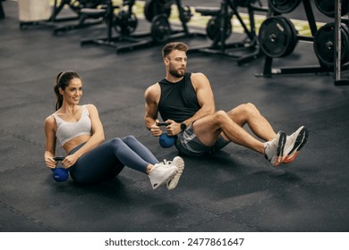 Fit muscular sportspeople doing russian twists with kettlebell on gym floor. - Powered by Shutterstock