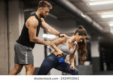 A fit muscular sportswoman is doing kettle bell row in a gym with her instructor. - Powered by Shutterstock