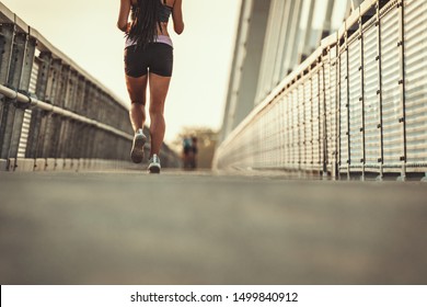 Fit muscular young woman runner sprinting at great speed outdoors on the river bridge. - Shutterstock ID 1499840912