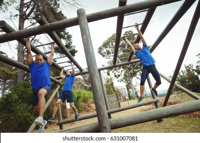 Fit people climbing monkey bars in bootcamp 