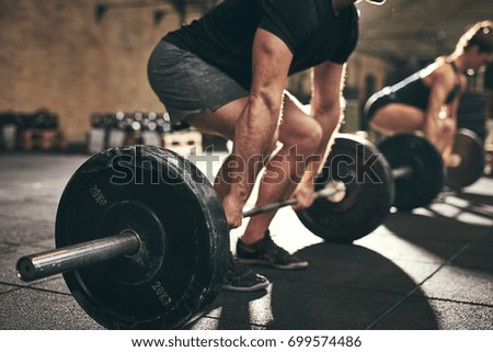Fit people doing deadlift exercise in gym. Horizontal indoors shot