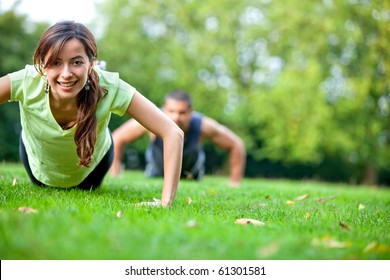 Fit people doing push-ups at the park - Powered by Shutterstock