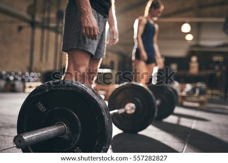 Fit people standing at barbells before exercise. Horizontal indoors shot