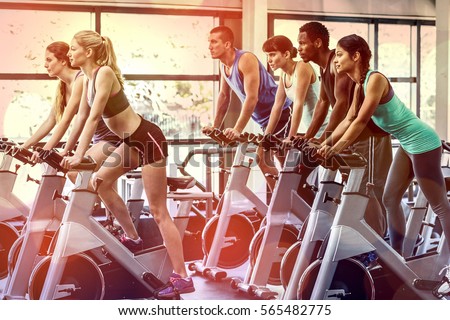 Fit people working out at spinning class in the gym