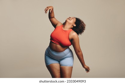 Fit plus size woman confidently displays her sportiness and flexibility through dance. Wearing sportswear and full of self-expression, she highlights the beauty of body positivity and diversity. - Powered by Shutterstock