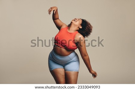 Fit plus size woman confidently displays her sportiness and flexibility through dance. Wearing sportswear and full of self-expression, she highlights the beauty of body positivity and diversity.