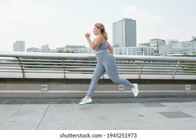 Fit plus size young woman listening to music when running outdoors and training for marathon - Powered by Shutterstock