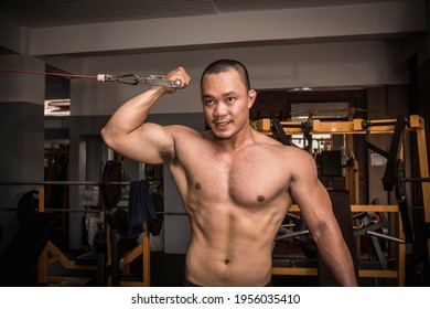 A Fit And Rugged Asian Guy Does Single Arm Bicep Cable Curls At The Gym. Arm Day Workout And Training.