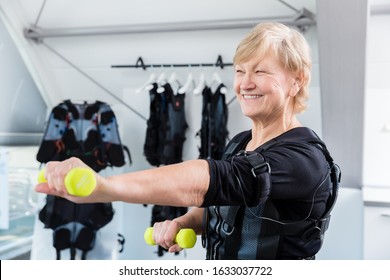 Fit Senior lady staying fit with dumbbell exercise in wireless ems gym