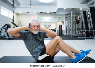 Fit senior man in gym working his abs, doing crunches.