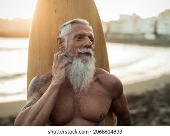 Fit senior man having fun practicing surf on tropical beach - Elderly healthy people lifestyle and extreme sport concept - Powered by Shutterstock