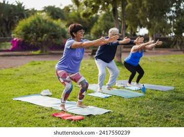 Fit senior people doing yoga exercise at city park - Healthy lifestyle and joyful elderly concept - Powered by Shutterstock