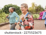 Fit senior people running at city park - Group of elderly friends doing sport workout together outdoor - Main focus on center mature woman face