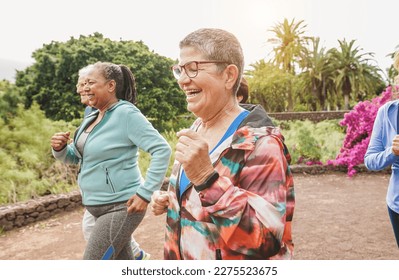 Fit senior people running at city park - Group of elderly friends doing sport workout together outdoor - Main focus on center mature woman face - Powered by Shutterstock