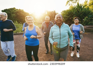 Fit senior people running at city park - Group of elderly friends doing sport workout together outdoor - Main focus on african woman face - Powered by Shutterstock