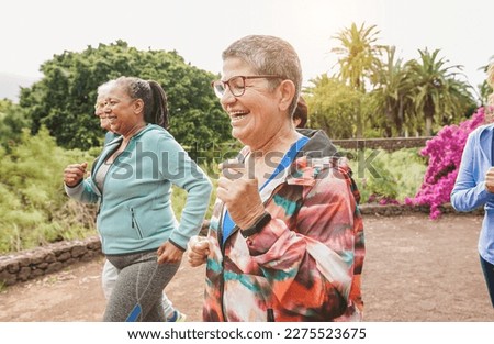 Fit senior people running at city park - Group of elderly friends doing sport workout together outdoor - Main focus on center mature woman face