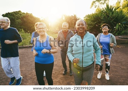Fit senior people running at city park - Group of elderly friends doing sport workout together outdoor - Main focus on african woman face