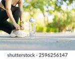A fit and slim Asian female runner is tie a shoes and prepare herself before starting her running. Woman left a water bottle beside while she
