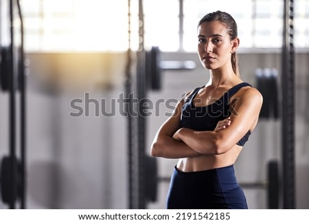 Fit, slim and serious woman with arms crossed, feeling confident about her body and health while standing in gym. Portrait of a sporty and determined woman ready to exercise to stay in healthy shape