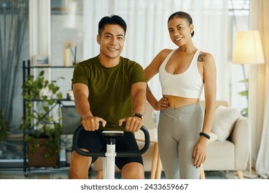 Fit smiling diverse couple exercising on bike at home - Powered by Shutterstock