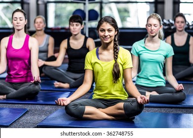 Fit smiling group doing yoga in gym